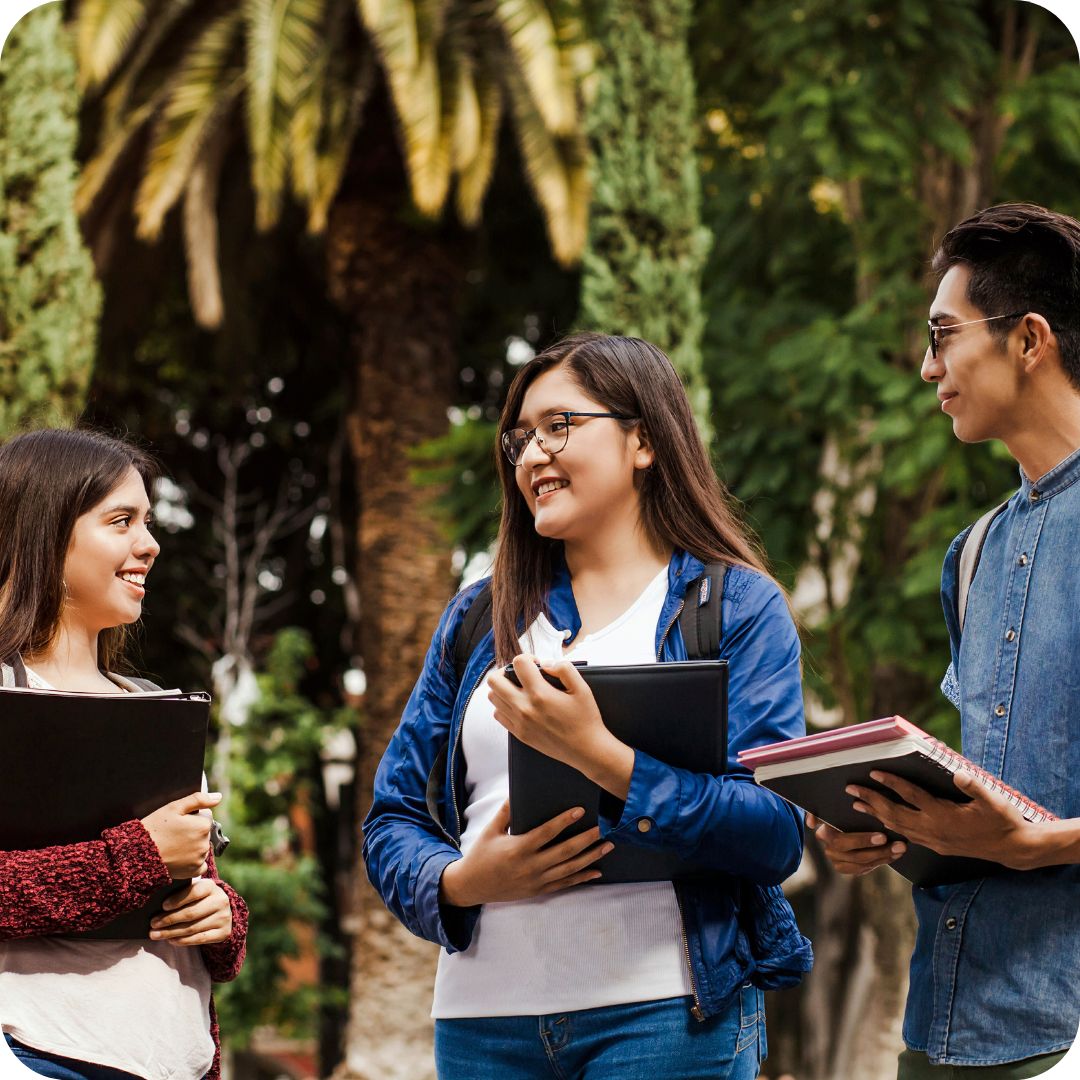 A group of international students holding books and folders in a park at Campsie Campus