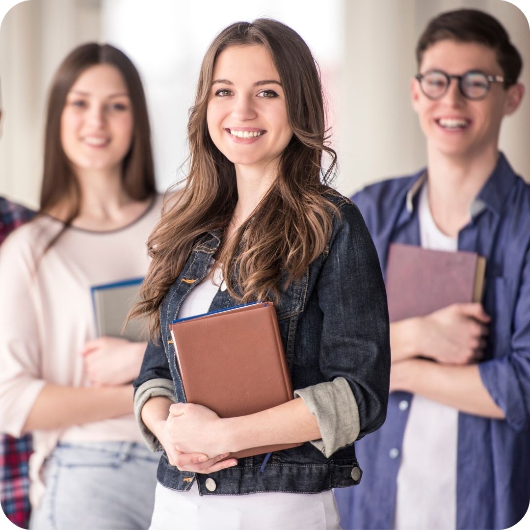 A group of domestic students holding books in a white wall background.